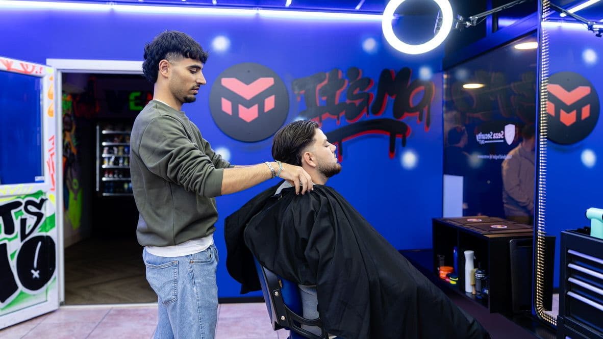 Barber knipt met de tondeuse bij de ItsMo-graffiti